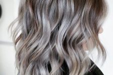 medium-length hair with silver highlights that accent the natural silver greys, and waves add interest to the hairstyle