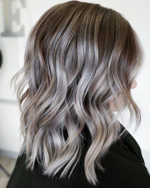 Medium length hair with silver highlights that accent the natural silver greys, and waves add interest to the hairstyle