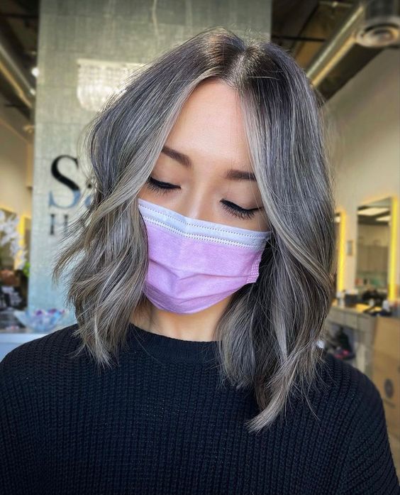 Medium length layered hair with grey balayage and natural greys and some waves is a cool and catchy solution