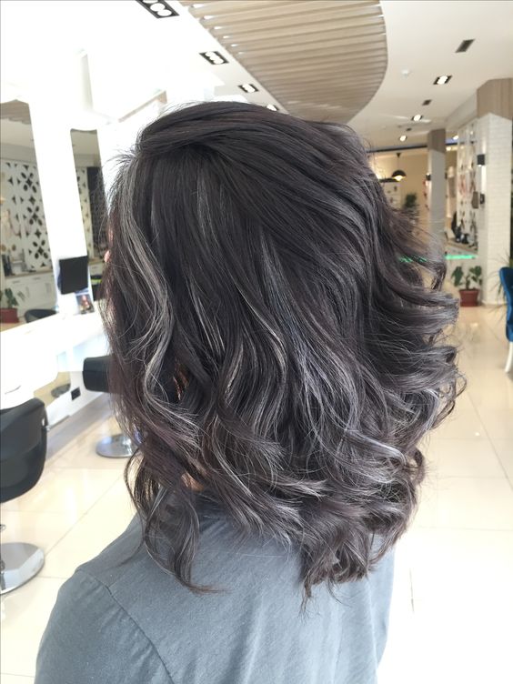 Medium length volumetric dark hair with grey highlights and waves looks very chic and bold and brings a natural look