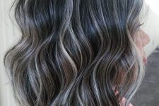 medium-length wavy black hair with silver balayage that helps naturally grey hair blend in