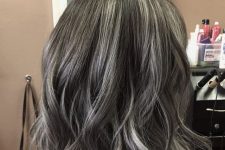 shoulder-length black hair with silver balayage and waves looks very natural, chic and beautiful