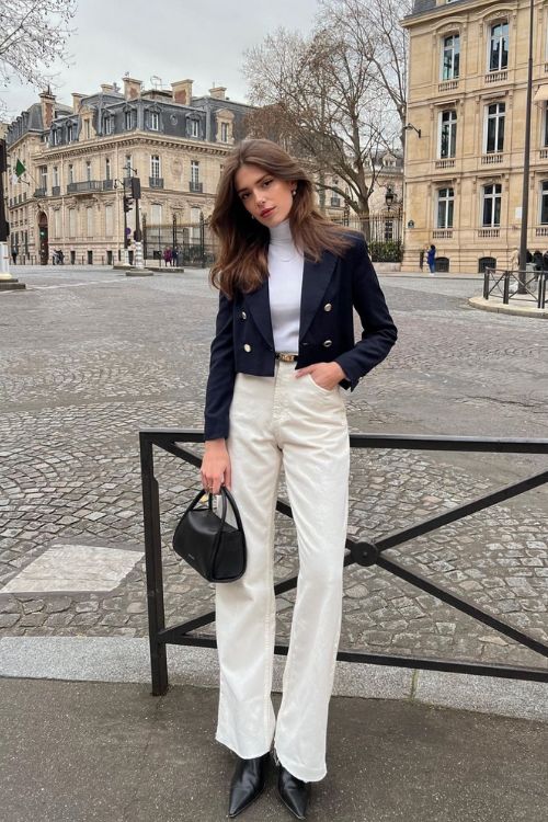 an old money outfit with a white turtleneck, creamy jeans, a navy cropped blazer, black shoes and a black bag