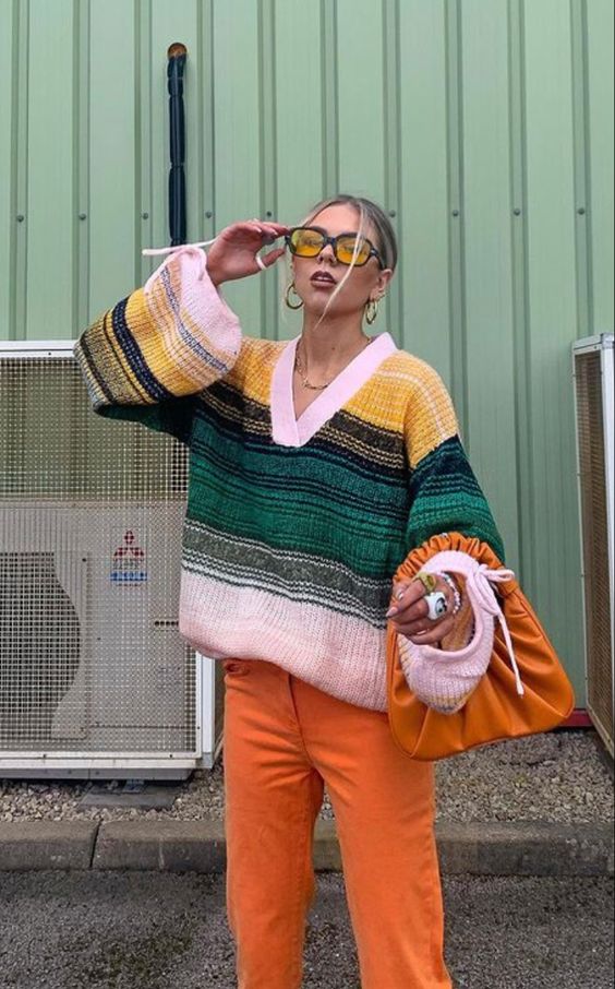 a colorful outfit with a striped oversized jumper, orange pants and an orange bag