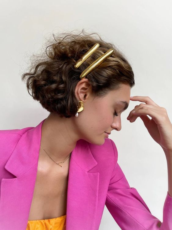 a bold and curly bob with two polished gold hair pins and statement earrings looks amazing