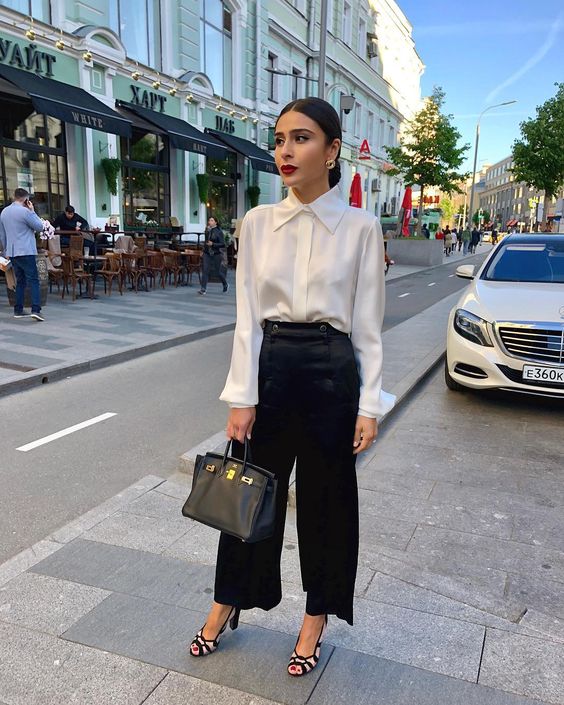 a classic corporate core look with a white silk button down, black wilk pants, black and white shoes and a black bag