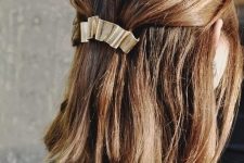 32 a classy half updo with a bump on top and straight hair down and a metallic hair barrette for a modern holiday party look