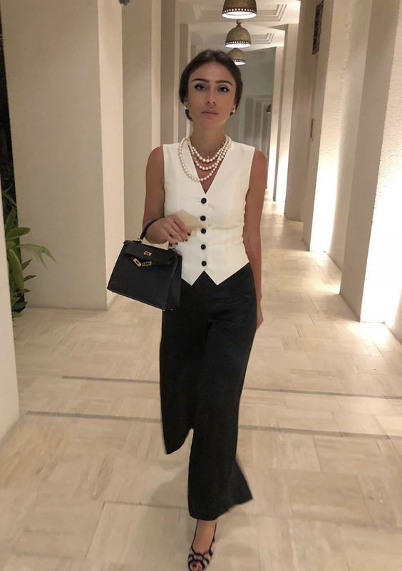 a perfect office look with a white waistcoat, black wideleg pants, black shoes, a small bag and pearl strands