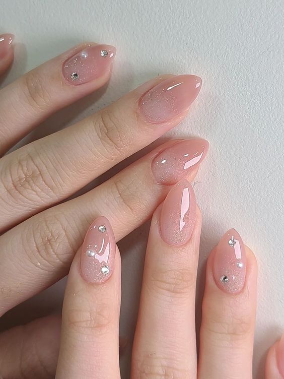 glitter nude stiletto nails with rhinestones and pearls on some fingers are a cool idea for a special occasion like a wedding