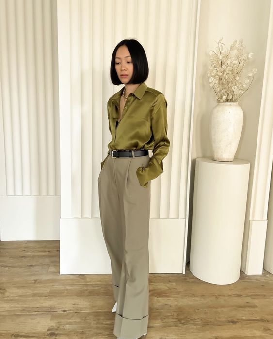 a lovely office outfit with a green silk button down, olive green wideleg pants, white shoes and a black belt