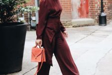 38 a burgundy jumpsuit with a catchy waist detail, brown shoes and an orange bag for a fall work look