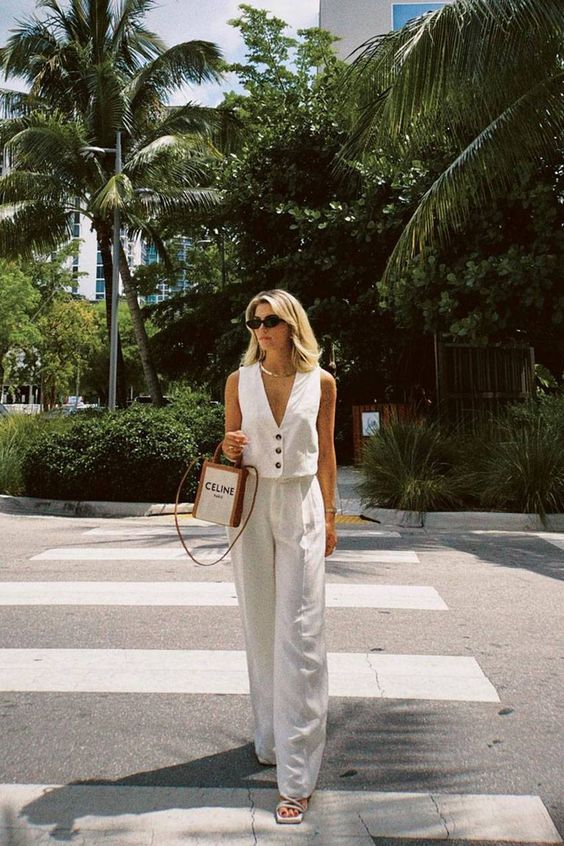 An all white summer outfit with a waistcoat, wideleg pants, a small bag and lace up shoes