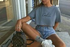53 a 90s inspired outfit with a cropped t-shirt, blue denim shorts, white trainers and grey socks plus a brown backpack