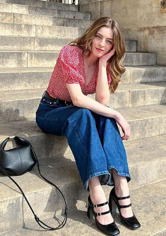 a Parisian chic outfit with a pink printed blouse, blue jeans, black Mary Jane shoes and a small black bag is cool
