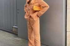 a Peach Fuzz pantsuit with an oversized blazer, a yellow bag and trainers are a super trendy sporty outfit