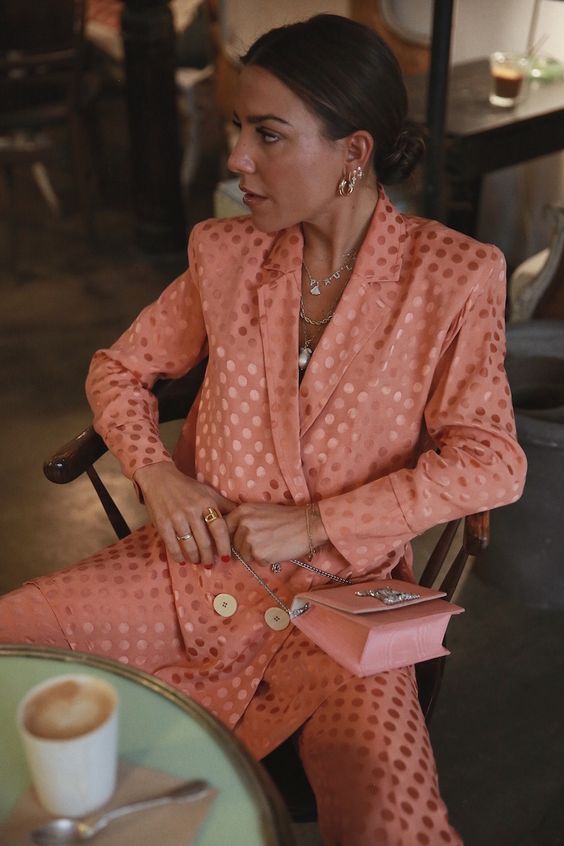 a Peach Fuzz pantsuit with polka dot print, a pink bag and multiple jewelry pieces for a trendy look this spring