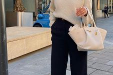 a beautiful quiet luxury look with a neutral oversized jumper, black pants, black shoes and a white bag plus a chain necklace