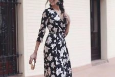 a black floral maxi dress with long sleeves and a V-neckline, black tassel earrrings, metallic shoes and a clutch