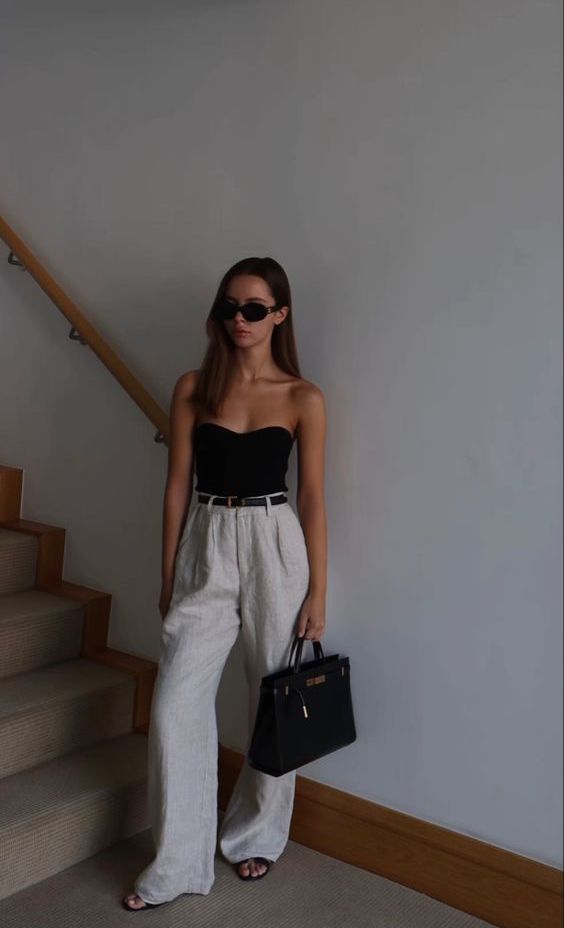 a black strapless top, neutral high waisted trousers, black slippers and a black tote for summer