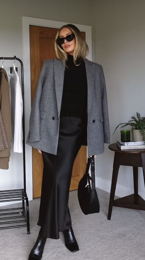 a black sweater, a slip maxi skirt, black square toe boots, a grey blazer and a black bag compose a quiet luxury look