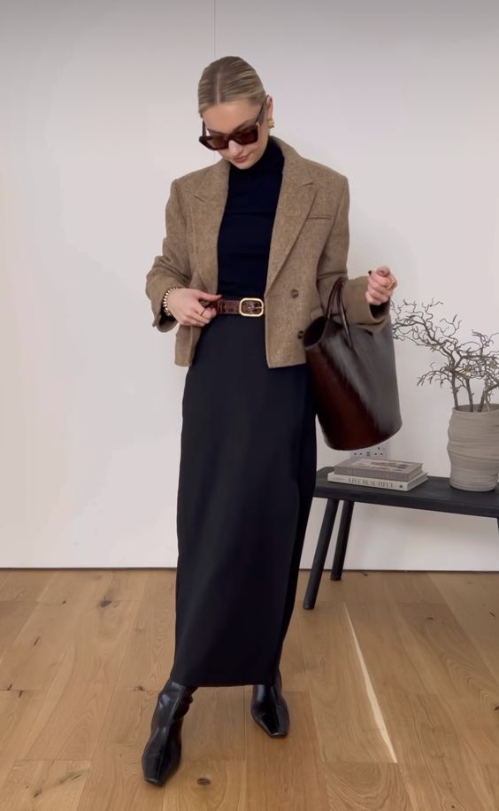 a black turtleneck, a black maxi skirt, black boots, a beige cropped blazer and a burgundy tote