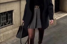 a black turtleneck, a grey pleated mini, a black coat, black tights, burgundy knee boots and a black bag