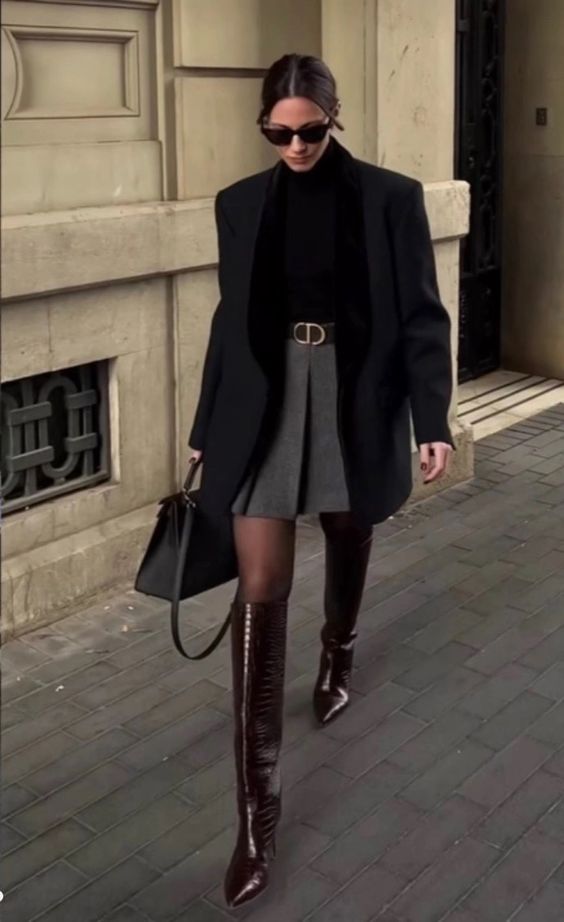 a black turtleneck, a grey pleated mini, a black coat, black tights, burgundy knee boots and a black bag