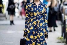 a bold fall wedding guest dress, a navy with yellow floral prints, black boots and a black bucket bag makes a statement with its contrast