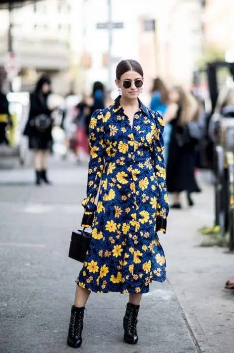 a bold fall wedding guest dress, a navy with yellow floral prints, black boots and a black bucket bag makes a statement with its contrast