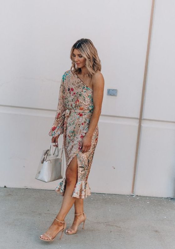 a bold floral one shoulder midi dress with a slit and a long sleeves plus statement earrings for a summer wedding