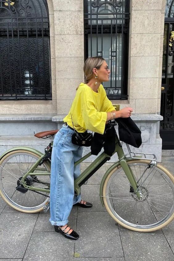 a bold spring look with a yellow long sleeve top, blue baggy jeans, black Mary Jane shoes and a black bag