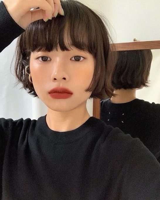 A brunette ear length bob with outgrown bangs and messy texture is a lovely idea