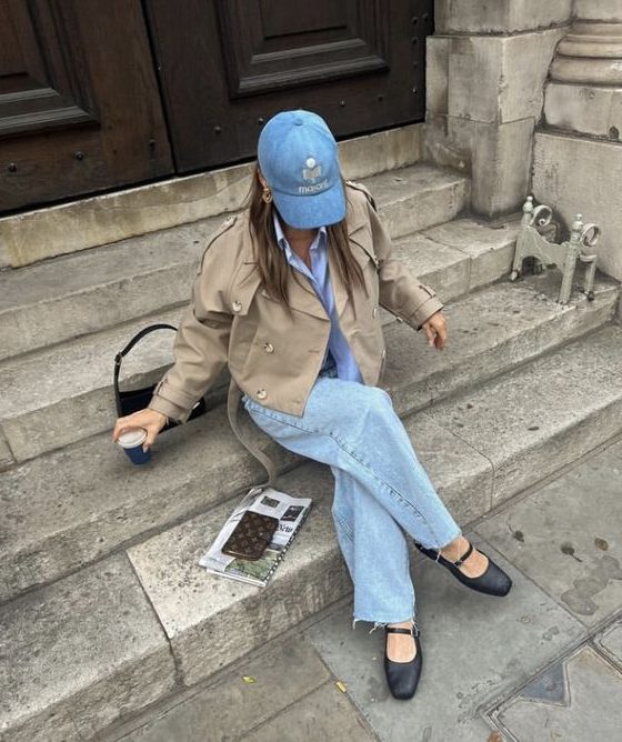 a casual look with a blue shirt, blue wideleg jeans, black Mary Jane shoes, a beige cropped jacket and a denim cap