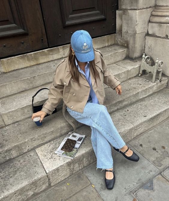 a casual look with a blue shirt, blue wideleg jeans, black Mary Jane shoes, a beige cropped jacket and a denim cap