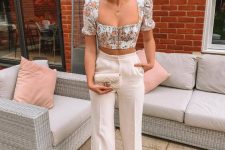 a casual wedding guest look with a floral crop top with puff sleeves and a square neckline, white trousers and a white bag