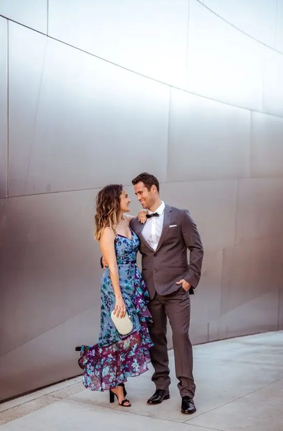 a chic bright wedding guest midi dress with ruffles and a floral print, black shoes and a tiny white clutch for a black tie wedding