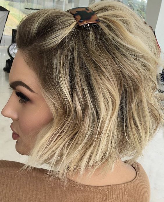 A chin length bob styled as a half updo with some hair up secured with a barrette and waves down