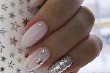 a classy glam almond manicure with nude to milky nails and two accents, a silver glitter and a silver star one,