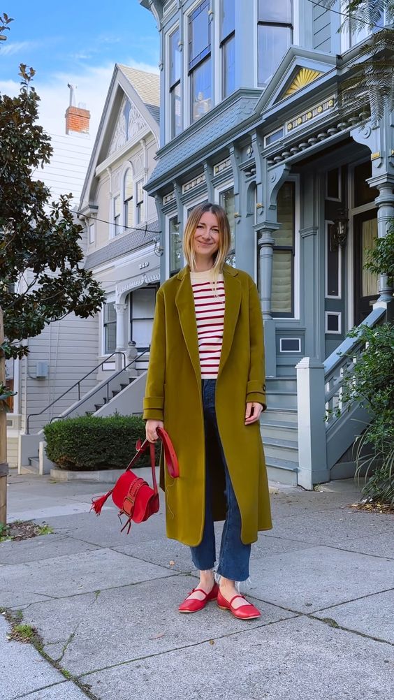 a colorful outfit with a striped top, blue jeans, red Mary Jane shoes, a mustard coat and a red bag