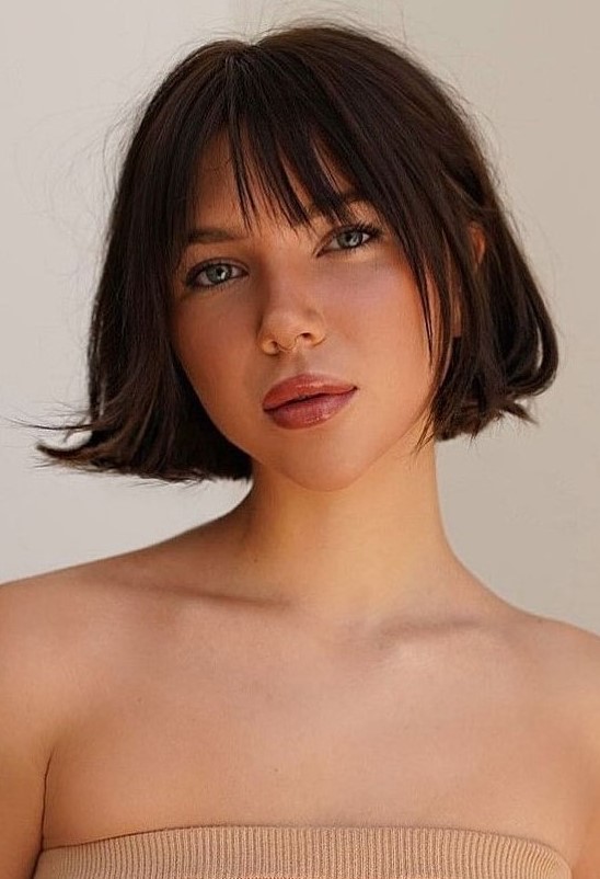 a dark brunette jaw-line bob with face-framing layers and wispy bangs and a bit of volume is a great idea for any season