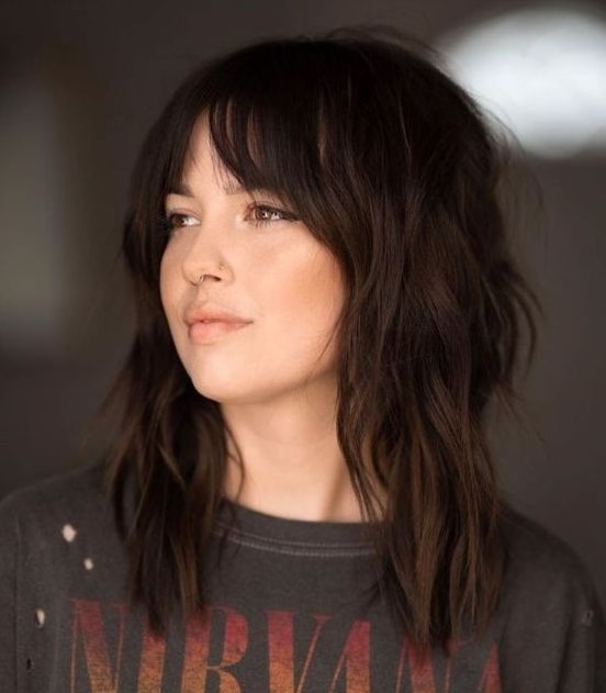 a dark brunette medium wolf cut with bottleneck bangs and messy waves is a cool and trendy idea for now