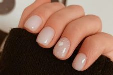 a delicate nude manicure with milky and blush nails and a heart plus polkd dots on the ring finger is amazing for a cute look