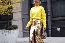 a fashionable look with a gold yellow sweatshirt, a gold sequin midi pencil skirt, gold shoes and a snakeskin print bag