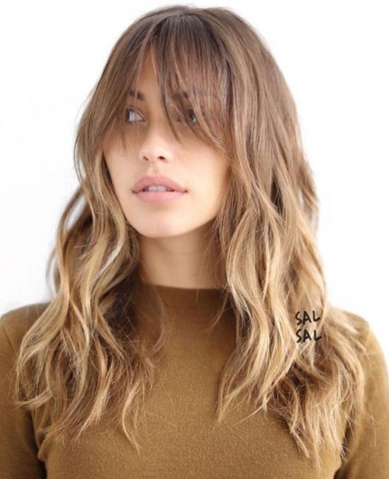 a long layered haircut with a light ombre and long bangs plus messy waves