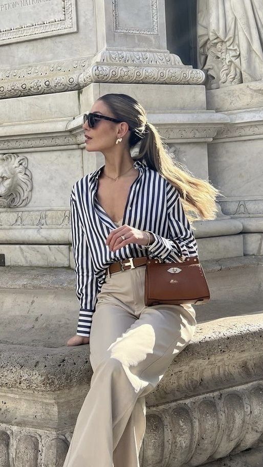 a lovely old money look with a striped shirt, neutral pants, a brown belt and a small brown bag plus statement earrings