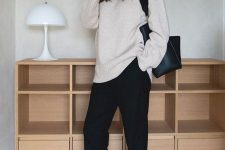 a minimalist outfit with a creamy sweater, black trousers, a black tote and white Mary Jane shoes