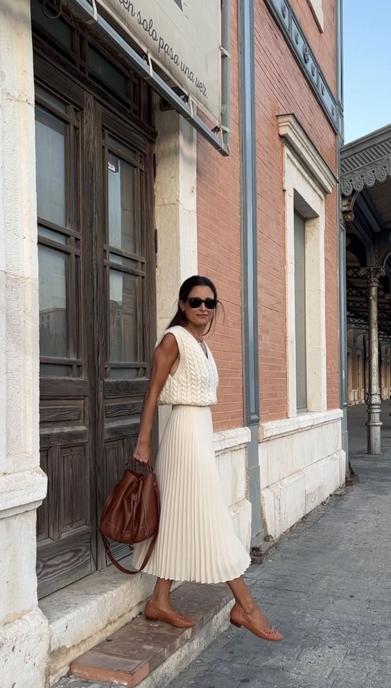 a neutral crochet sleeveless top, a pleated midi skirt, brown flats and a brown bag to compose a cool summer old money look