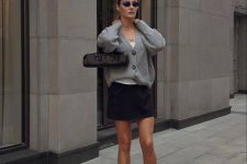 a neutral top, a black mini skirt, a grey oversized cardigan, silver Mary Jane flats, grey socks and a small bag