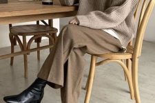 a quiet luxury look with an oversized shirt, a greige jumper, brown trousers, black boots is simple and cool