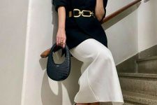 a quiet luxury outfit for a special occasion with an oversized black blazer with chain, a white midi skirt, black and gold shoes and a small navy bag
